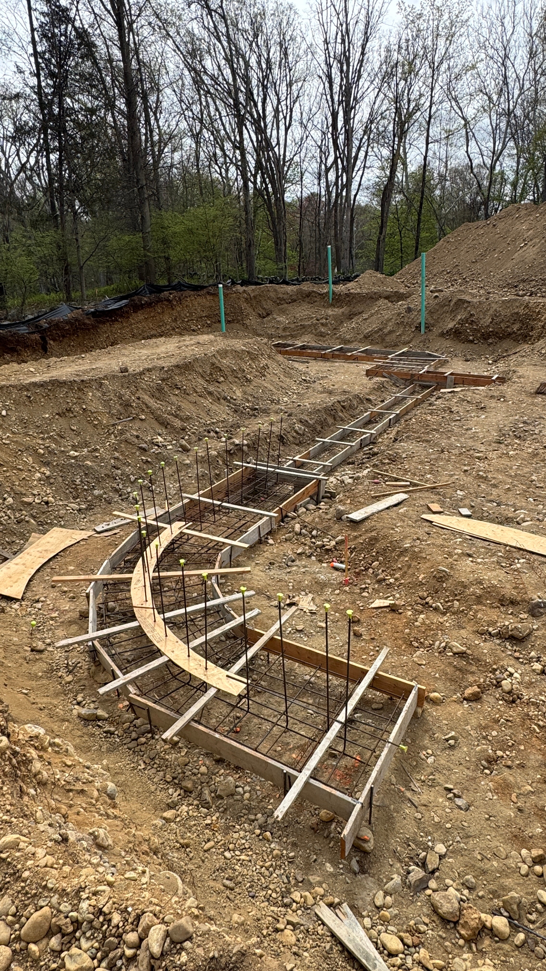 Curved and rectilinear footing formwork with rebar cages set in place, ready for a concrete foundation pour.